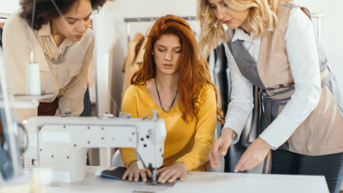 Two Women showing young lady how to sew