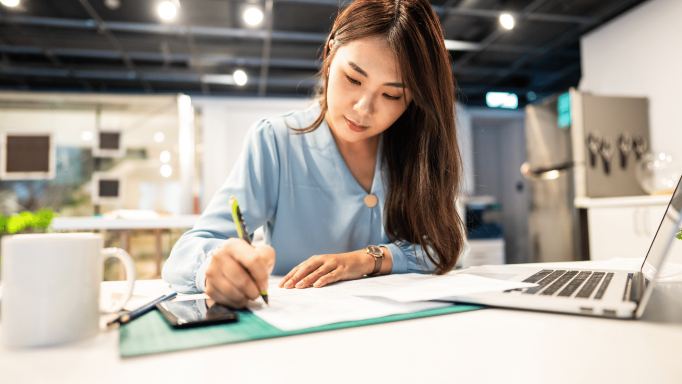 Asian woman writing at her desk